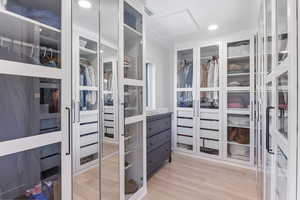 Walk in closet featuring attic access and light wood-style flooring