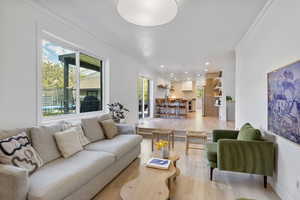 Living area featuring recessed lighting, ornamental molding, and light wood-style flooring