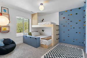 Bedroom featuring a custom rock wall, carpet flooring, and custom bunk beds