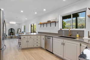 Kitchen featuring stainless steel appliances, open shelves, a sink, white cabinetry, and a peninsula
