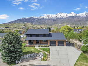 View of front of home with concrete driveway, a mountain view, an attached garage, a porch, and brick siding