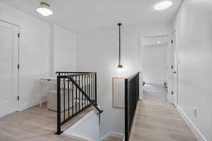 Hall featuring an upstairs landing, baseboards, and light wood-style floors