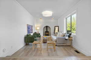 Sitting room with wood finished floors, visible vents, crown molding, and a wood stove