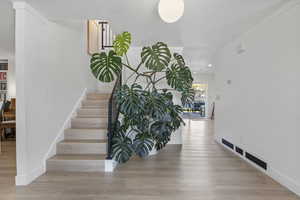 Interior space with ornamental molding, visible vents, wood finished floors, and baseboards