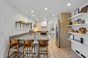 Kitchen featuring recessed lighting, a sink, stainless steel appliances, open shelves, and a peninsula