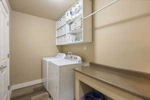 Laundry room with wood finished floors, washer and clothes dryer, laundry area, and baseboards
