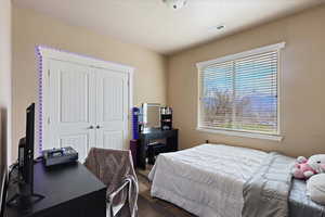 Bedroom with a closet, dark wood-style flooring, and visible vents