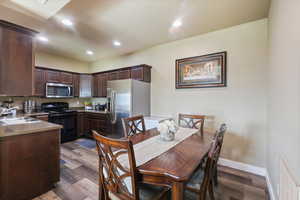 Dining area featuring dark wood-type flooring, visible vents, recessed lighting, and baseboards