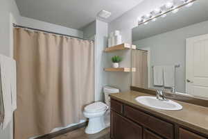 Full bathroom with wood finished floors, toilet, a textured ceiling, and vanity