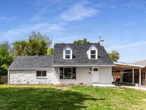 View of front of home with an attached carport, a chimney, a shingled roof, fence, and a front lawn