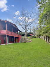 View of East side of  yard with a covered balcony & downstairs patio.