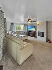 Living area with a ceiling fan, carpet, and a fireplace
