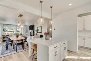Kitchen featuring white cabinets, a kitchen island, open floor plan, and light wood finished floors
