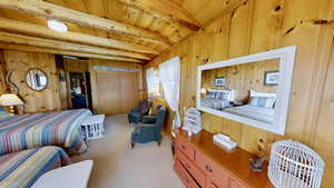 Bedroom with wooden walls, wooden ceiling, beam ceiling, and carpet floors