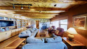 Living room featuring wood walls, wooden ceiling, beam ceiling, and wood finished floors