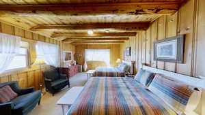 Carpeted bedroom featuring wood walls, wooden ceiling, and beam ceiling