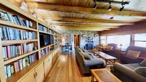 Living room with beam ceiling, light wood-type flooring, a fireplace, and wooden ceiling