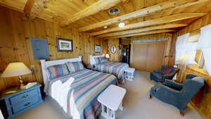 Carpeted bedroom with beamed ceiling, electric panel, visible vents, wood walls, and wood ceiling
