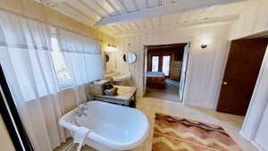 Ensuite bathroom with beam ceiling, connected bathroom, plenty of natural light, and tile patterned flooring