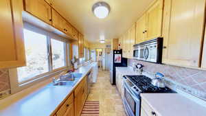 Kitchen featuring stainless steel appliances, light countertops, washer / dryer, backsplash, and a sink