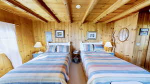 Bedroom featuring beamed ceiling, wooden walls, wooden ceiling, and carpet flooring