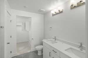 Primary bathroom with toilet, tile flooring, a sink, and double vanity