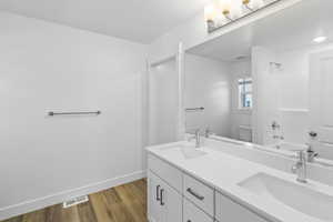 Full bathroom featuring double vanity, wood finished floors, toilet, and a window
