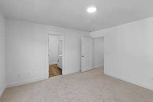Primary bedroom featuring light colored carpet, large window, and baseboards (View is different)