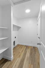 Clothes washing area with wood finished floors, laundry area, and baseboards
