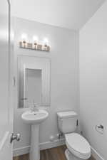 Bathroom with wood finished floors, toilet, and a sink