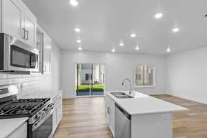 Kitchen featuring recessed lighting, decorative backsplash, appliances with stainless steel finishes, a sink, and light wood-type flooring