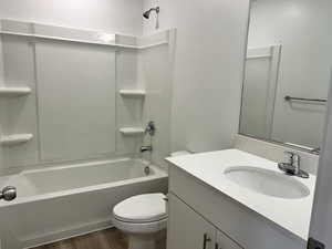 Bathroom featuring wood finished floors, vanity, toilet, and tub / shower combination