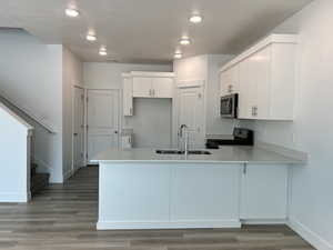Kitchen featuring a sink, stainless steel appliances, light countertops, baseboards, and a peninsula