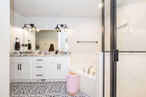 Full bath featuring double vanity, visible vents, a stall shower, tile patterned floors, and a garden tub. Private toilet with door.