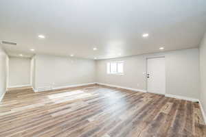 Below grade area with recessed lighting, visible vents, and light wood-type flooring