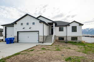 View of front of home featuring driveway, board and batten siding, and stone siding