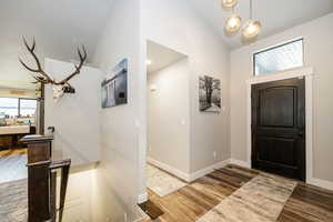 Entryway with wood finished floors, high vaulted ceiling, and baseboards