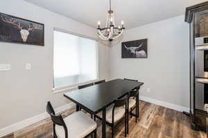 Dining room featuring a notable chandelier, dark wood-style floors, and baseboards