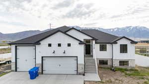 View of front of home with concrete driveway, a mountain view, stone siding, and board and batten siding
