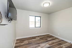 Empty room featuring visible vents, dark wood finished floors, and baseboards