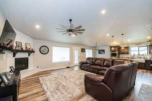 Living area featuring a tile fireplace, wood finished floors, and a ceiling fan