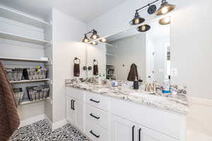 Full bathroom with tile patterned flooring, double vanity, a sink, and baseboards
