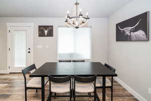 Dining room with a chandelier, baseboards, wood finished floors, and a wealth of natural light