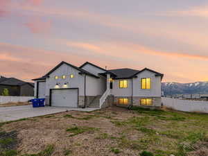 View of front of home featuring concrete driveway, a garage, board and batten siding, and fence