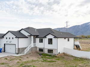 View of front of property with driveway, fence, board and batten siding, and a mountain view