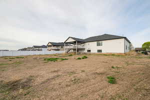 Rear view of property featuring stairs and fence