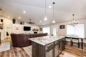 Kitchen featuring wood finished floors, ceiling fan with notable chandelier, decorative light fixtures, and vaulted ceiling