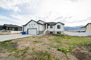 View of front facade featuring a garage, a mountain view, driveway, board and batten siding, and fence