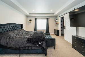 Bedroom featuring recessed lighting, a barn door, carpet flooring, baseboards, and a tray ceiling