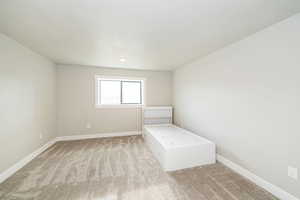 Unfurnished bedroom with light carpet and baseboards